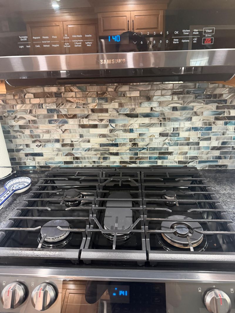 A gas cooktop and mosaic backsplash degreased and polished
