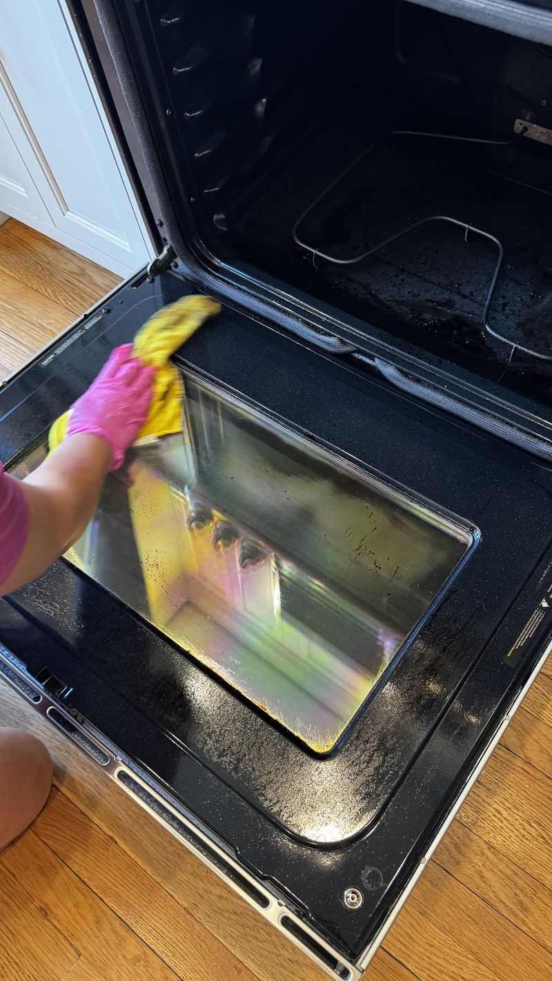 A RosyGloves cleaner wiping down an oven door