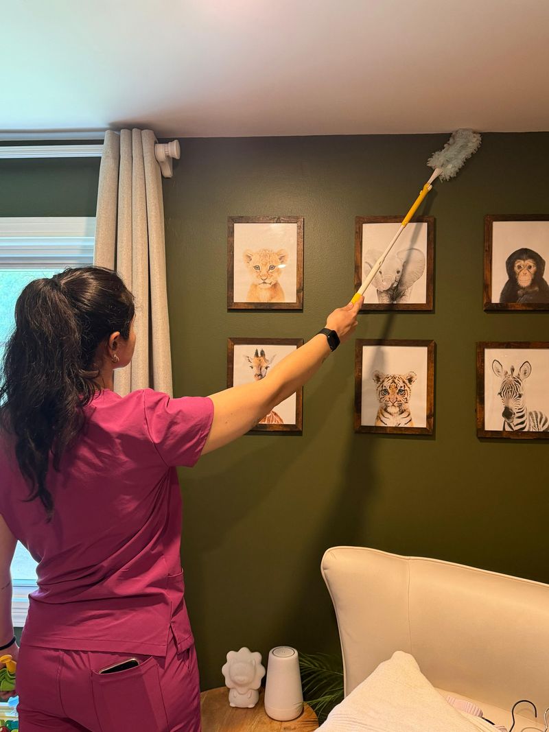 A RosyGloves cleaner dusting framed prints on a wall