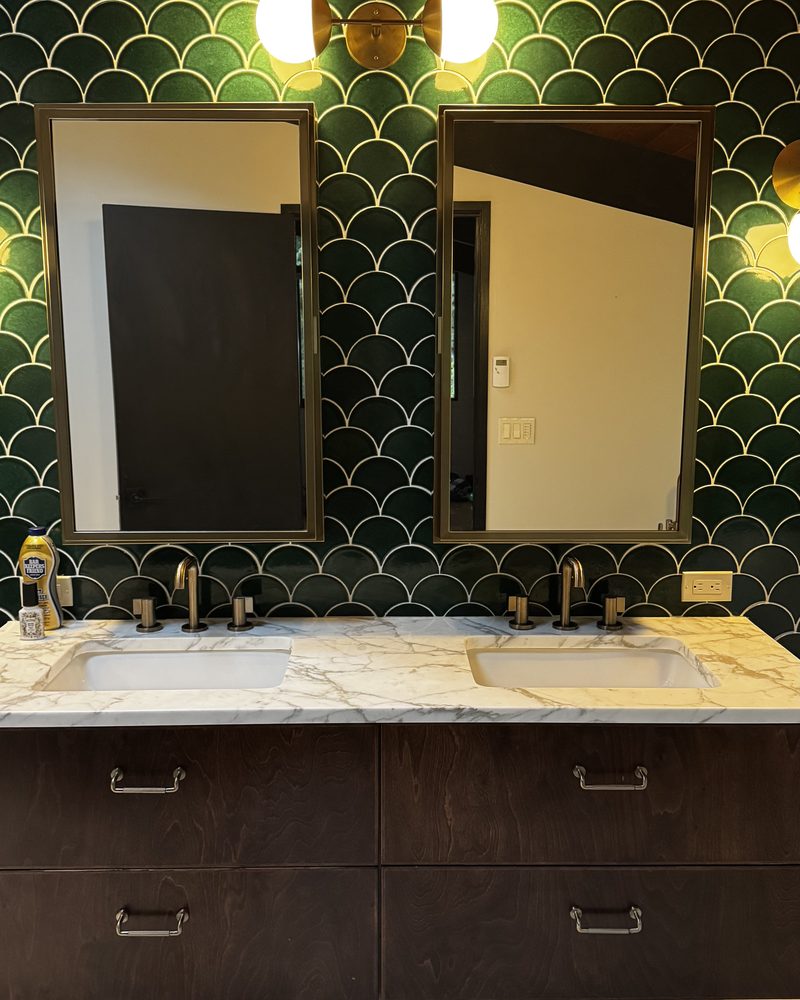 A double vanity and scalloped green tile wiped down
