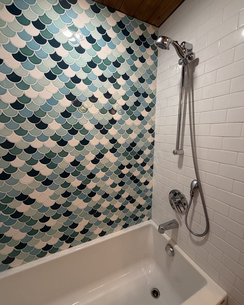 A tiled shower and tub scrubbed back to the grout