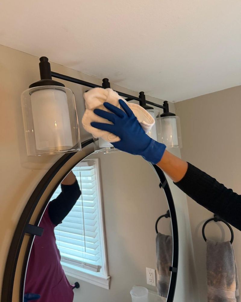 A RosyGloves cleaner wiping a glass light fixture